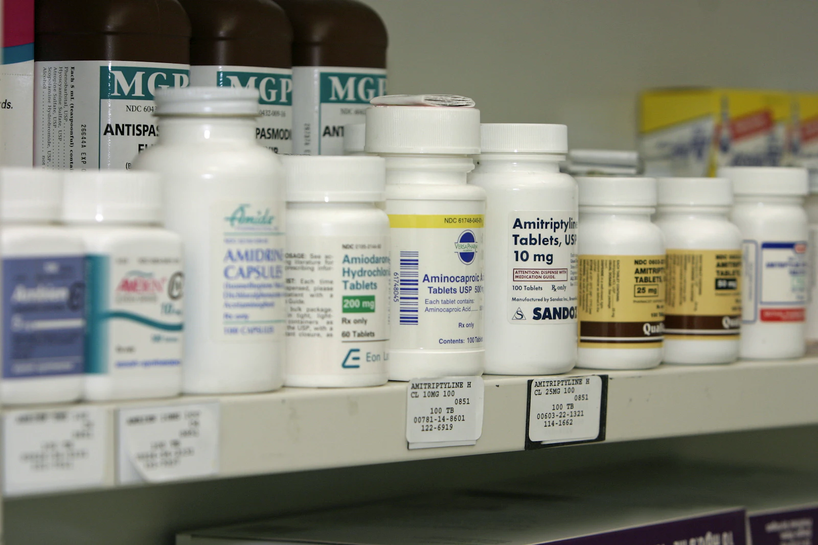 Labelled medicine bottles lined up on a dispensary shelf